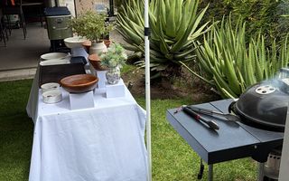 Montaje en jardín bajo un toldo blanco, con el asador al lado