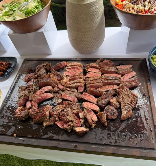 Tabla de cortes rebanados con floreros y ensaladas al fondo