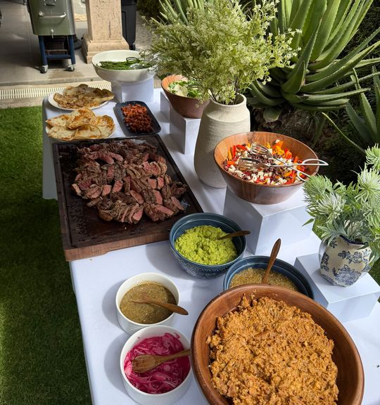 Guacamole, salsas, frijoles puercos y carpaccio de betabel servidos sobre la mesa con floreros