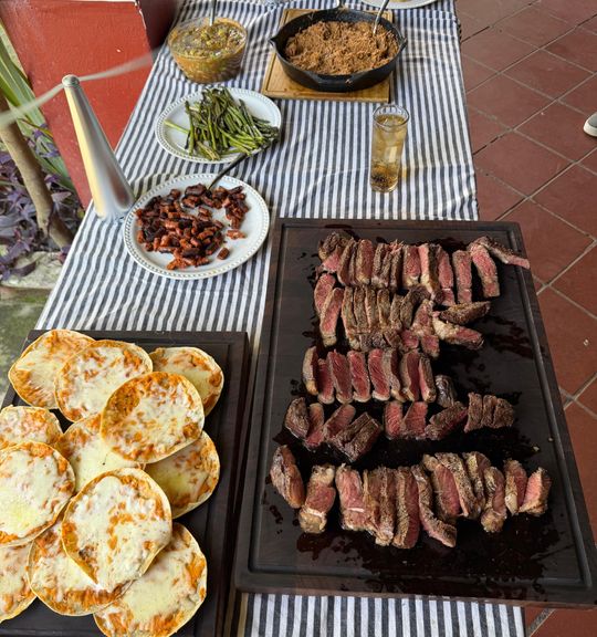 Quesadillas doradas, cortes rebanados, chistorra y frijoles sobre mantel de rayas